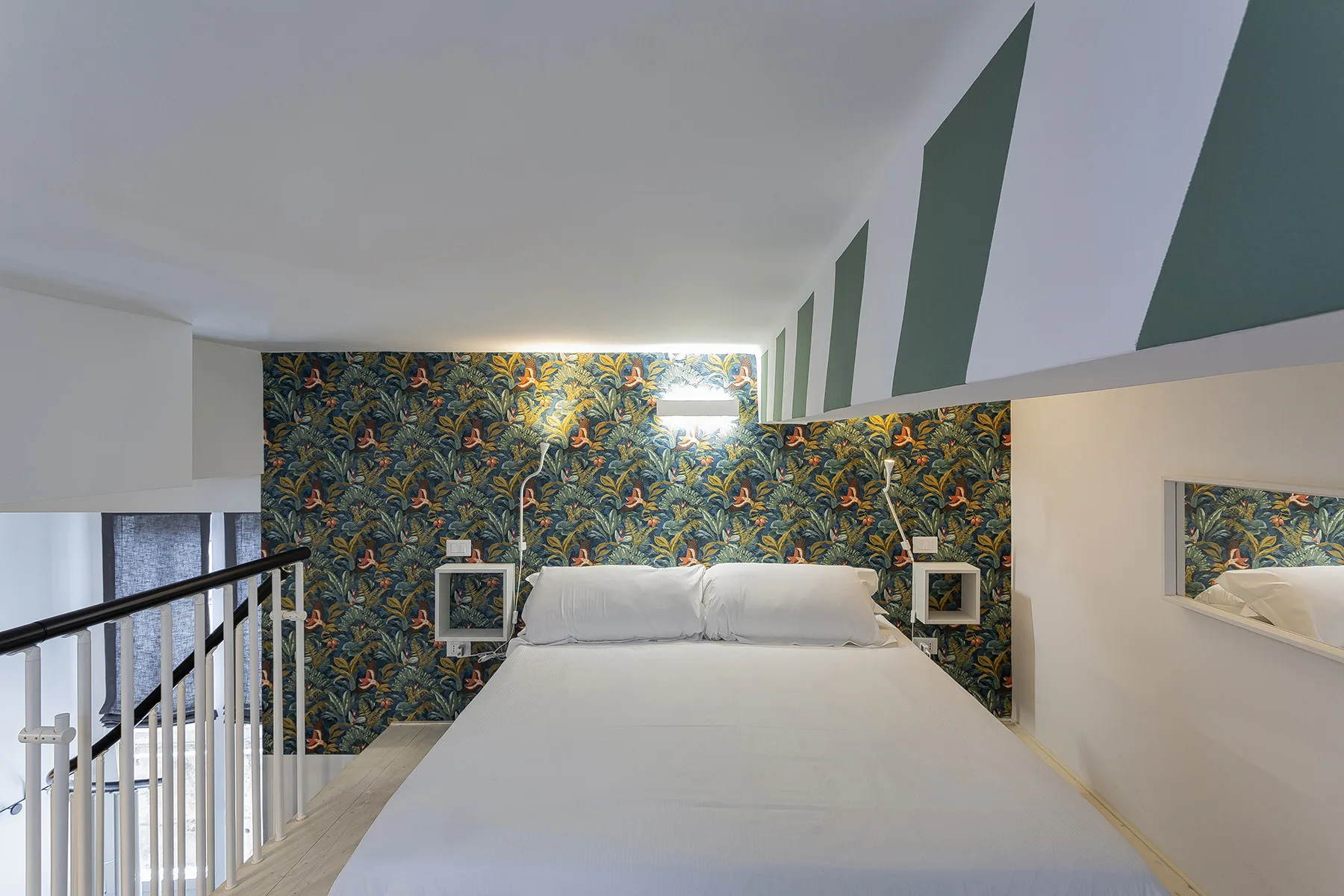 Un dormitorio con una cama frente a una pared de estampado colorido.