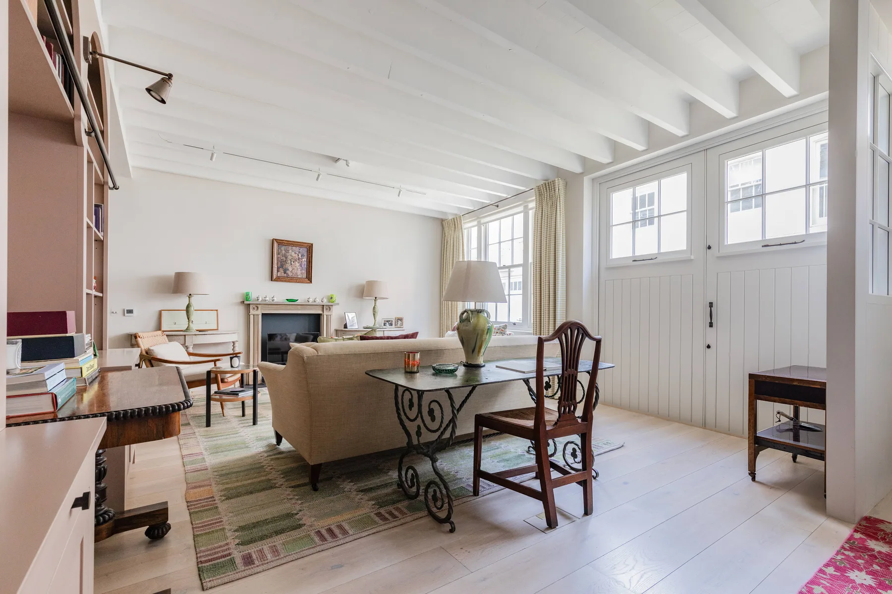 A bright living room with a seating area and a large desk beside the windows.