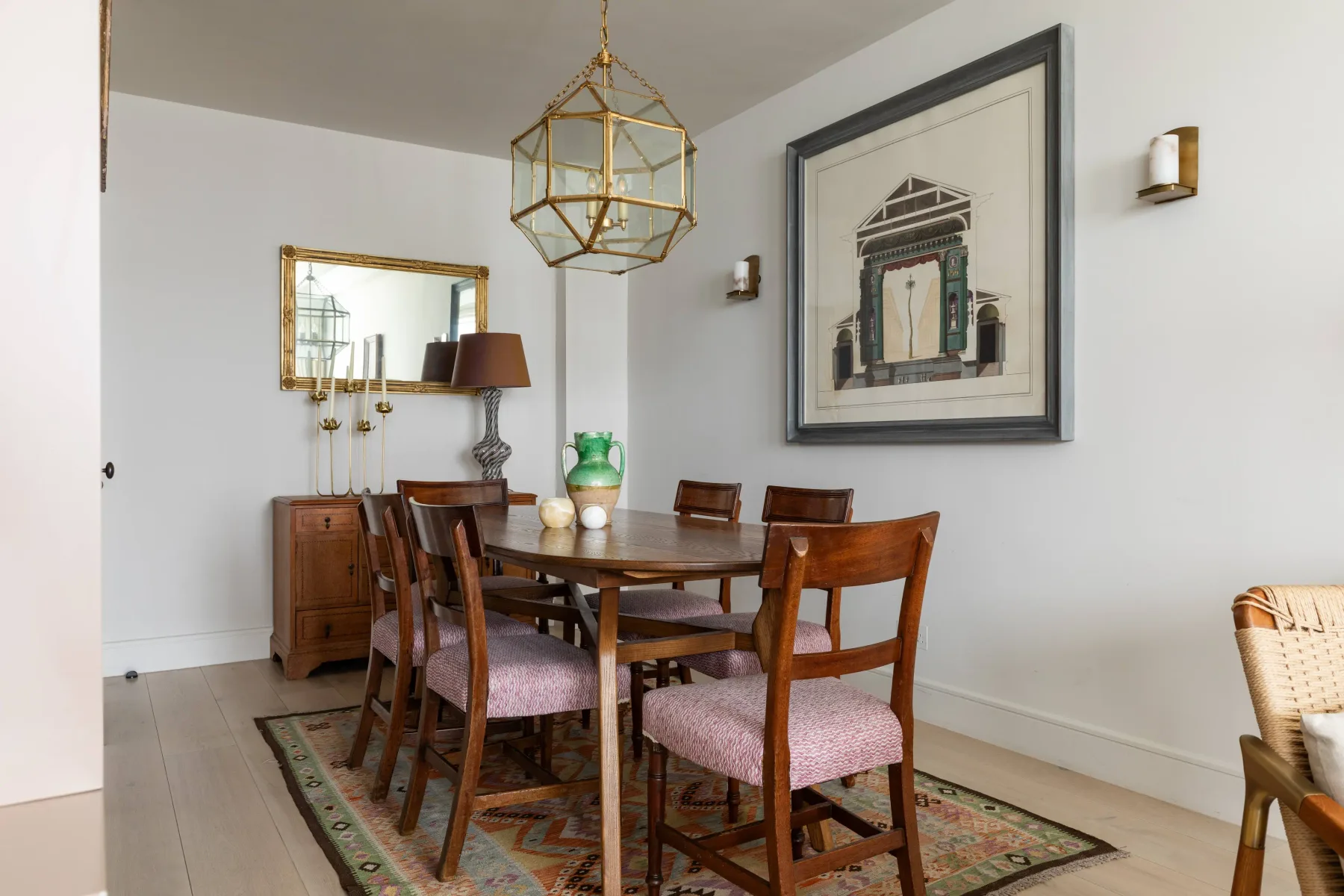 A dining room with a wooden table and upholstered chairs beneath a geometric pendant light.