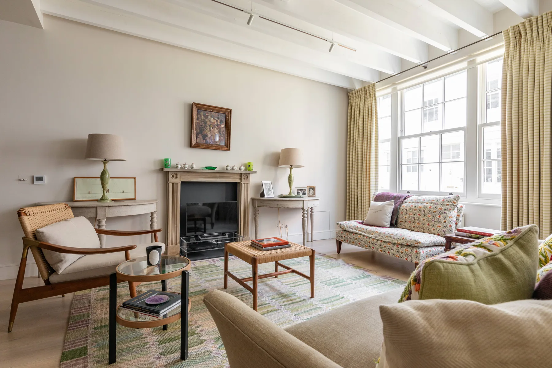 A bright living room with seating arranged around a fireplace and large windows.
