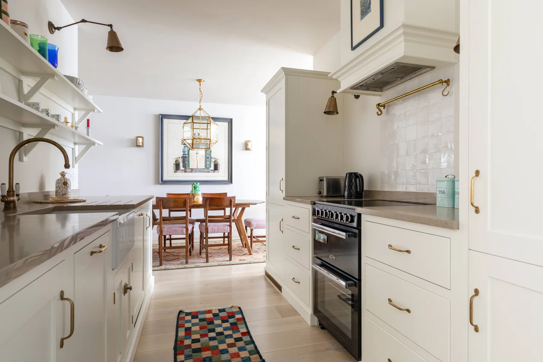 A bright kitchen with white cabinetry, a cooking range, and a dining table.
