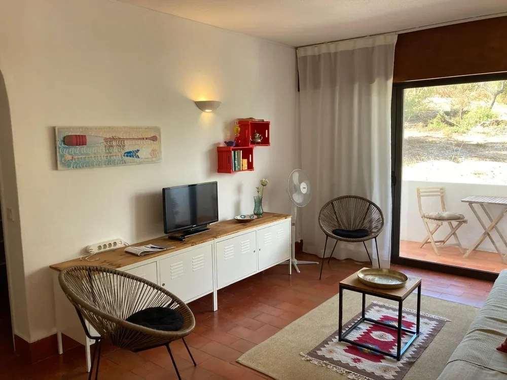 Una sala de estar con televisión, asientos y una puerta de vidrio que da a un patio.