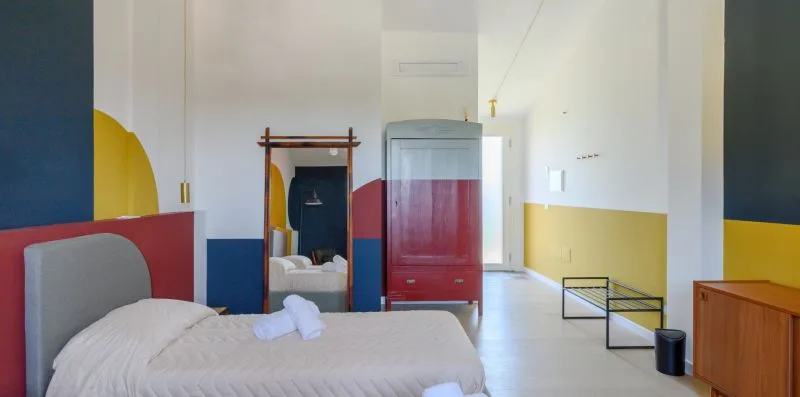 A colorful bedroom with a bed, wardrobe, and mirror.