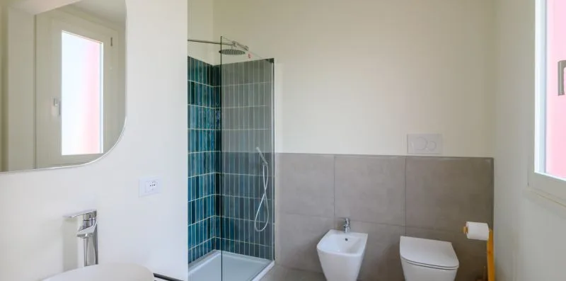 A bathroom with a glass shower, sink, and toilet.
