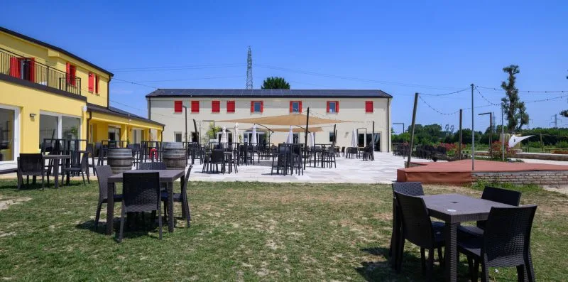 Una zona de comedor al aire libre con mesas y asientos junto a un edificio amarillo.
