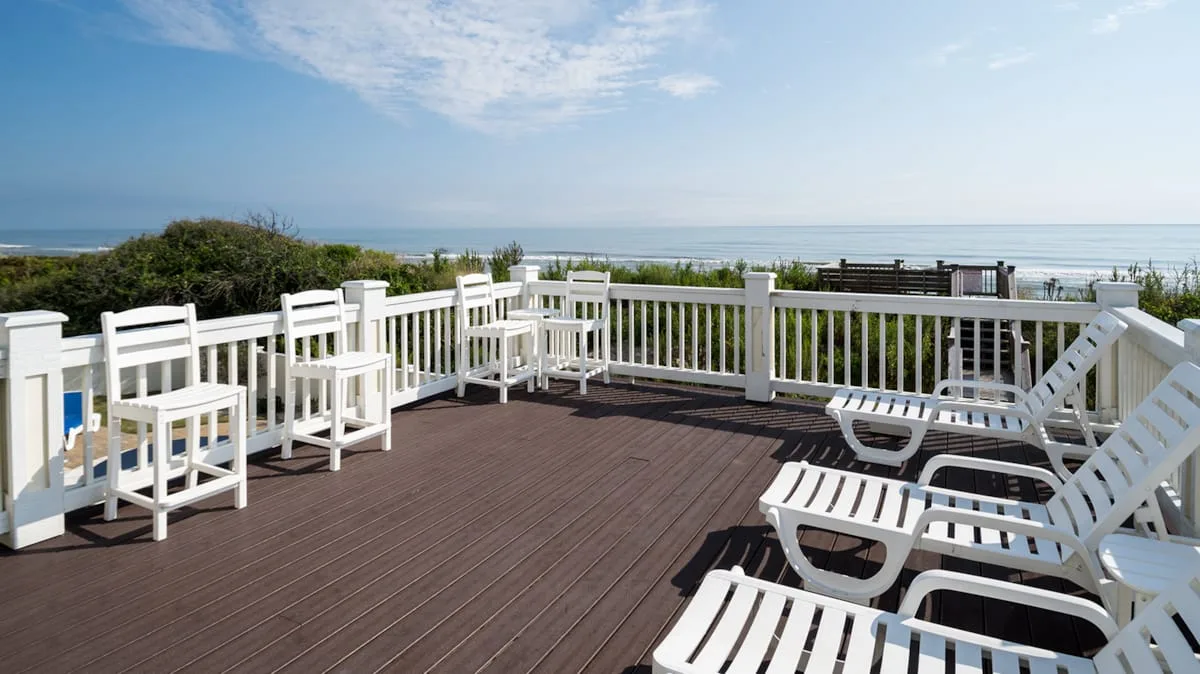 An outdoor deck with white seating overlooks the ocean.