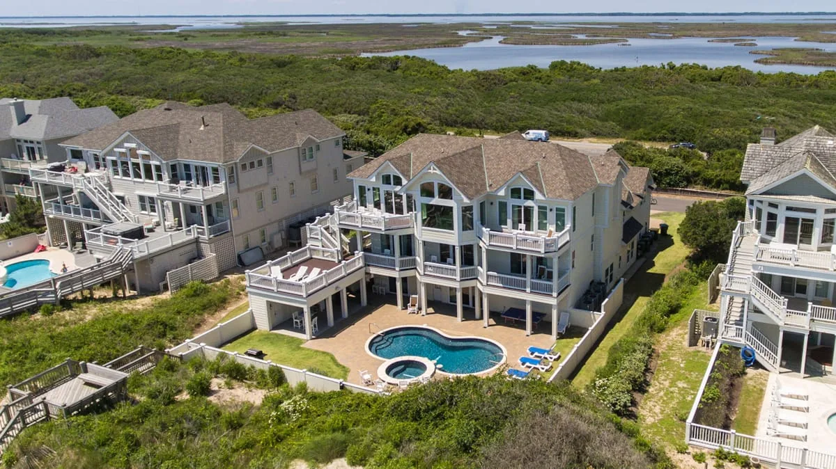 Aerial view of coastal houses beside a winding waterway and marshland.
