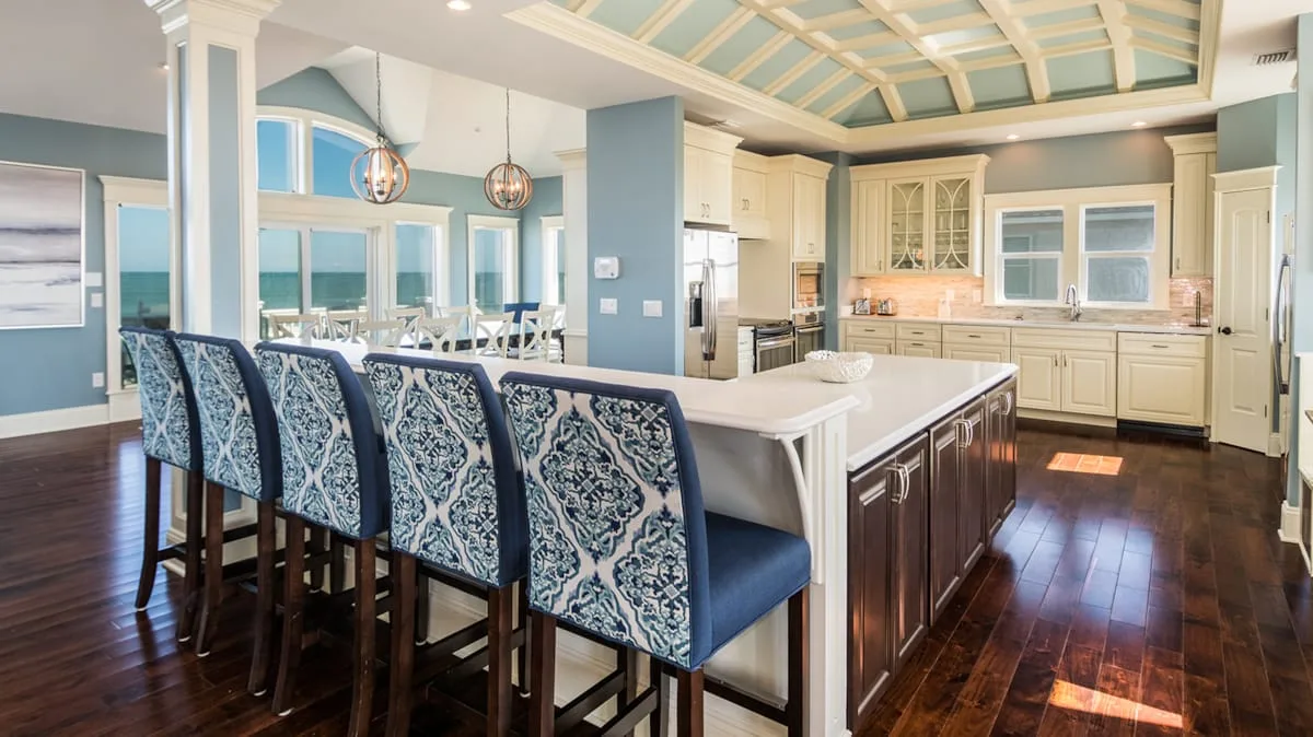 A spacious kitchen with a large island, bar seating, and pale cabinetry.