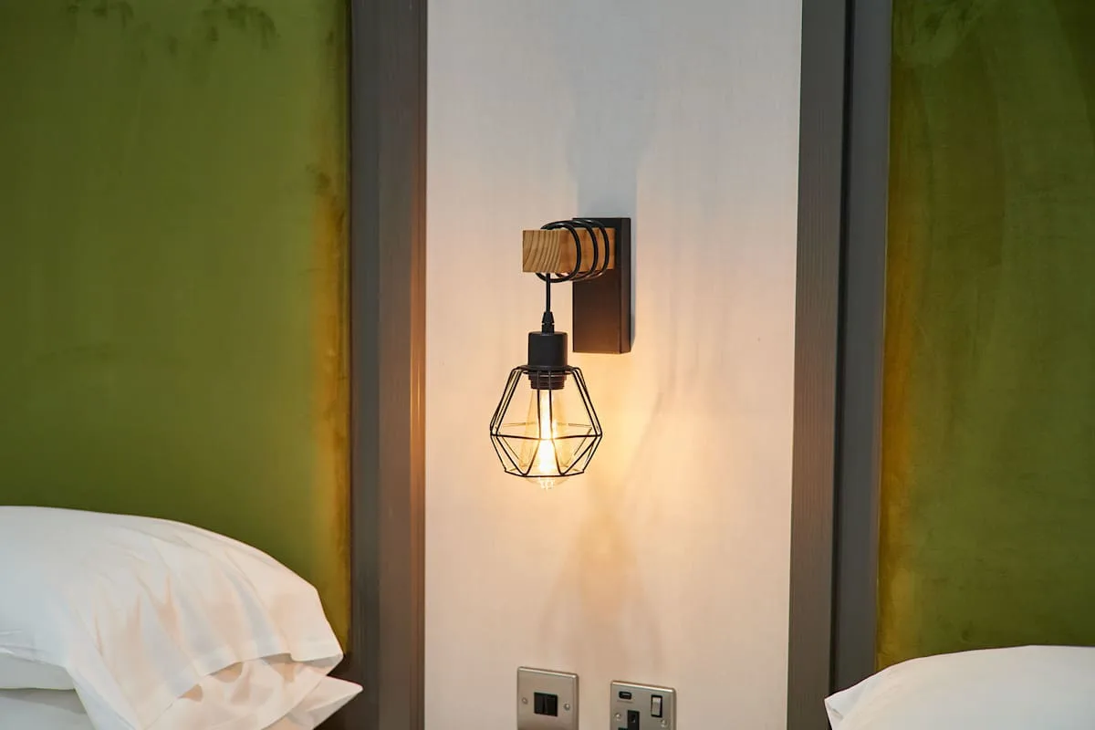 Dormitorio con una lámpara de pared entre dos camas.