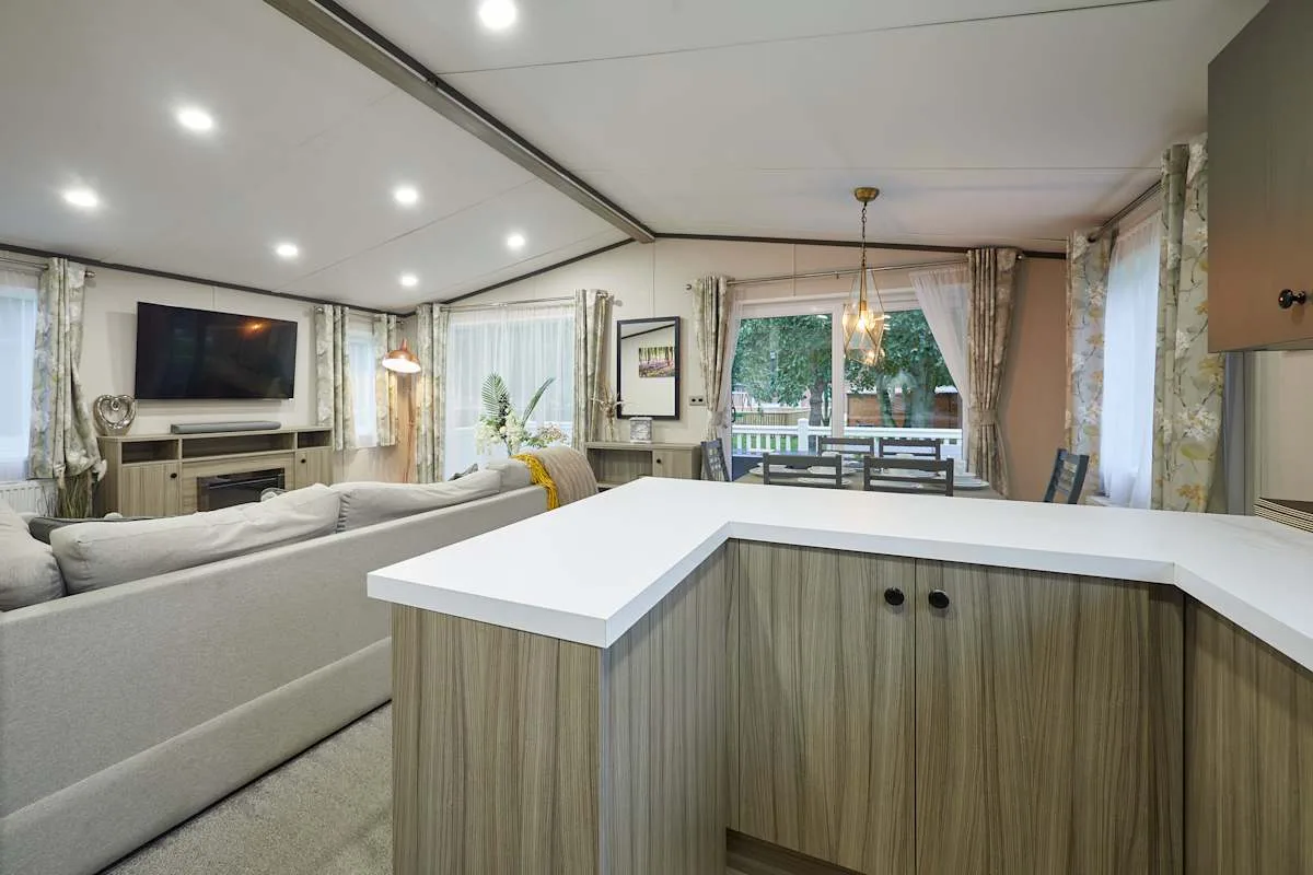 Una sala de estar y cocina abiertas con una isla blanca y asientos.