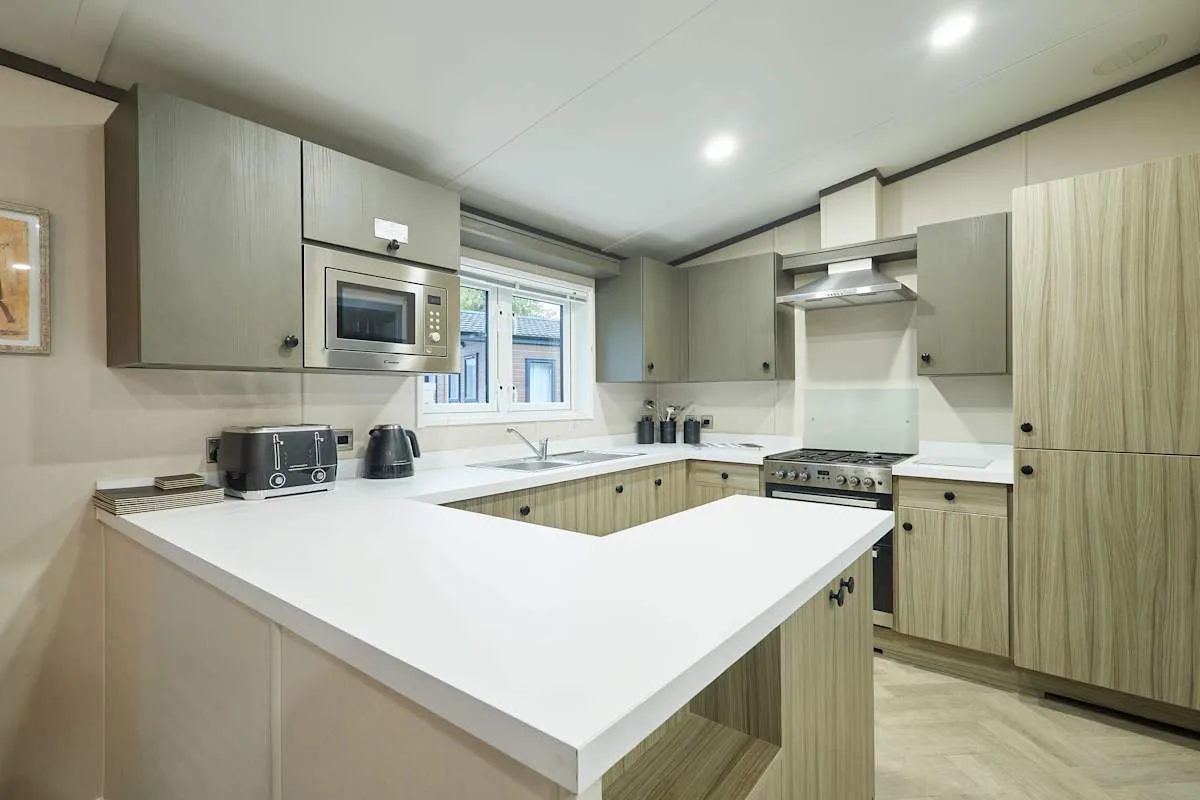 Una cocina moderna con gabinetes claros y una encimera blanca.