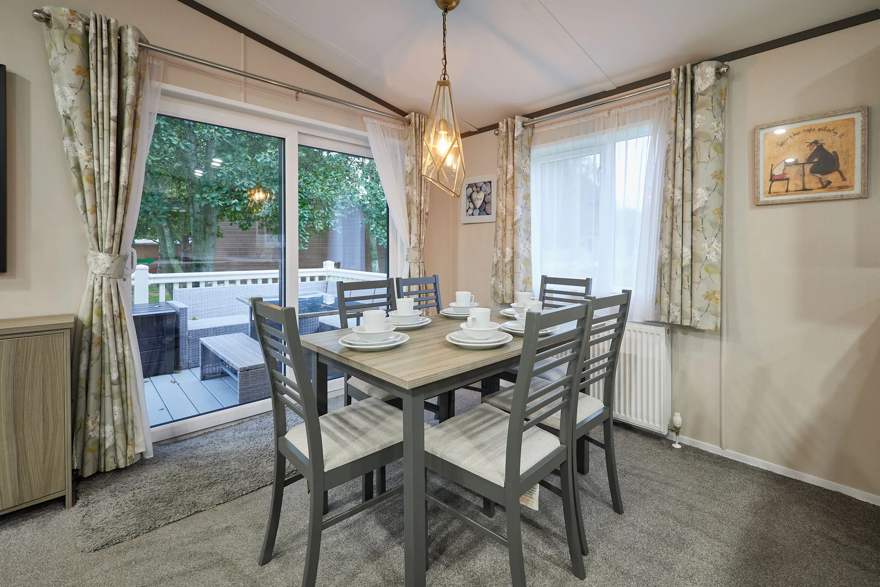 Un comedor con mesa y sillas junto a grandes ventanas que dan a un patio.