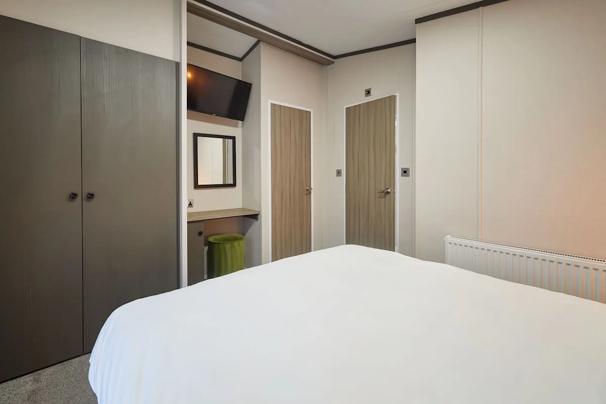 Un dormitorio con una cama bien arreglada, armarios y un escritorio.