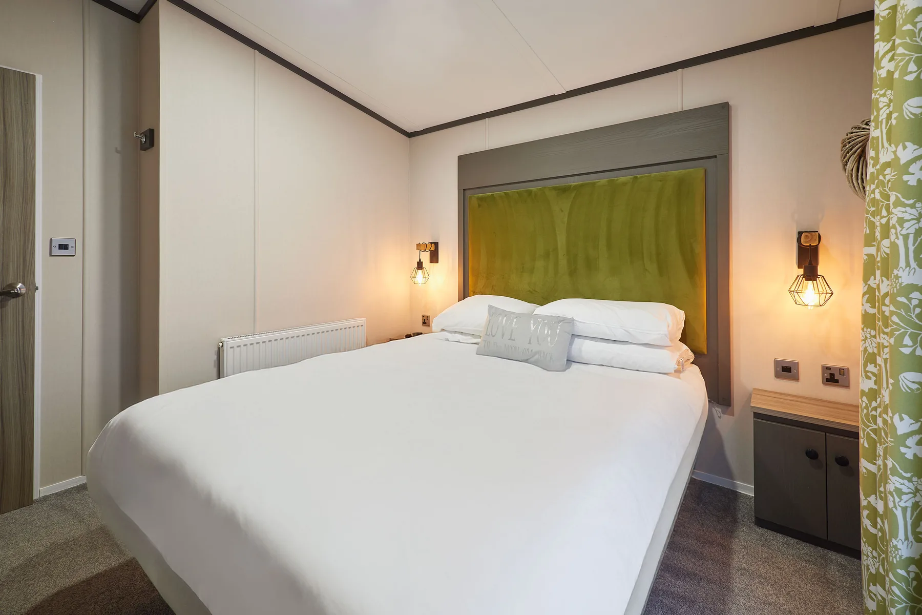 Un dormitorio con una cama bien tendida y un cabecero verde tapizado.