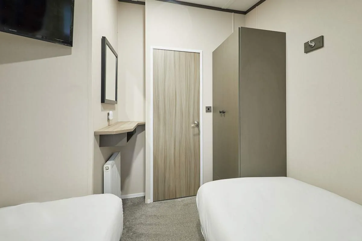 Un dormitorio con dos camas, un televisor y un armario.