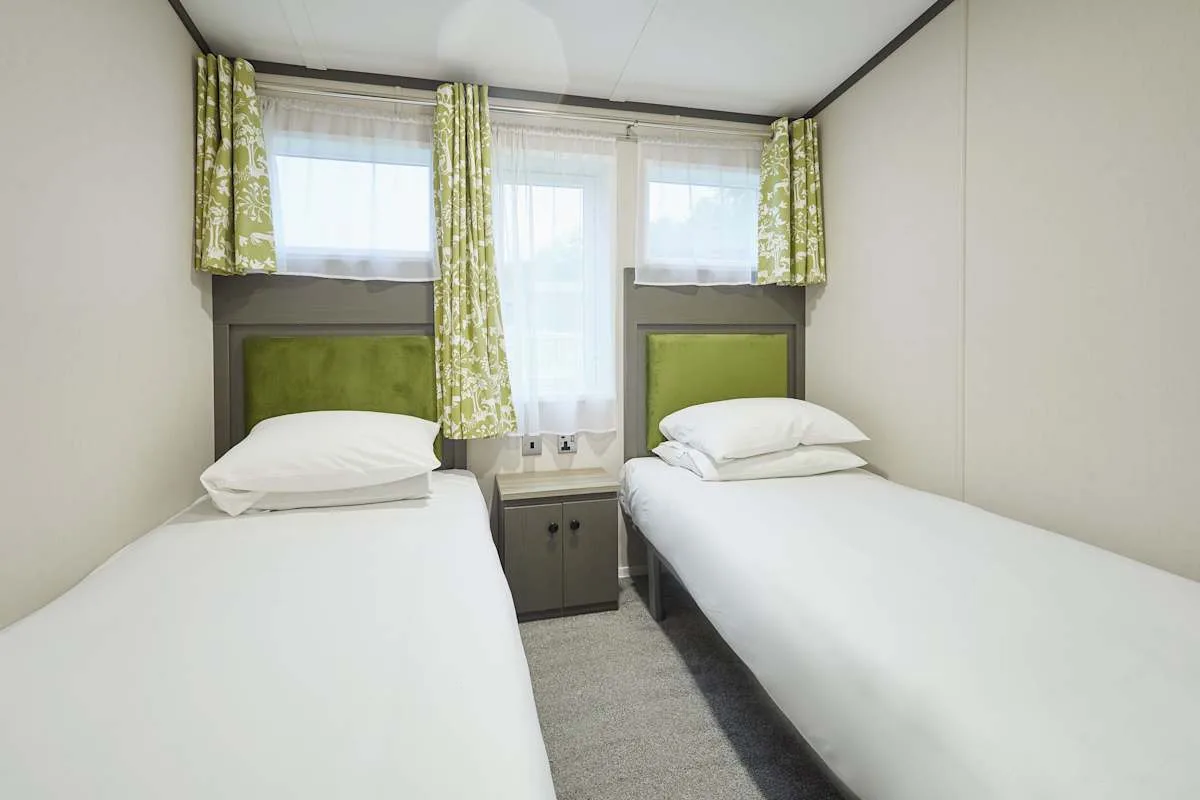 Un dormitorio con dos camas bajo ventanas con cortinas.