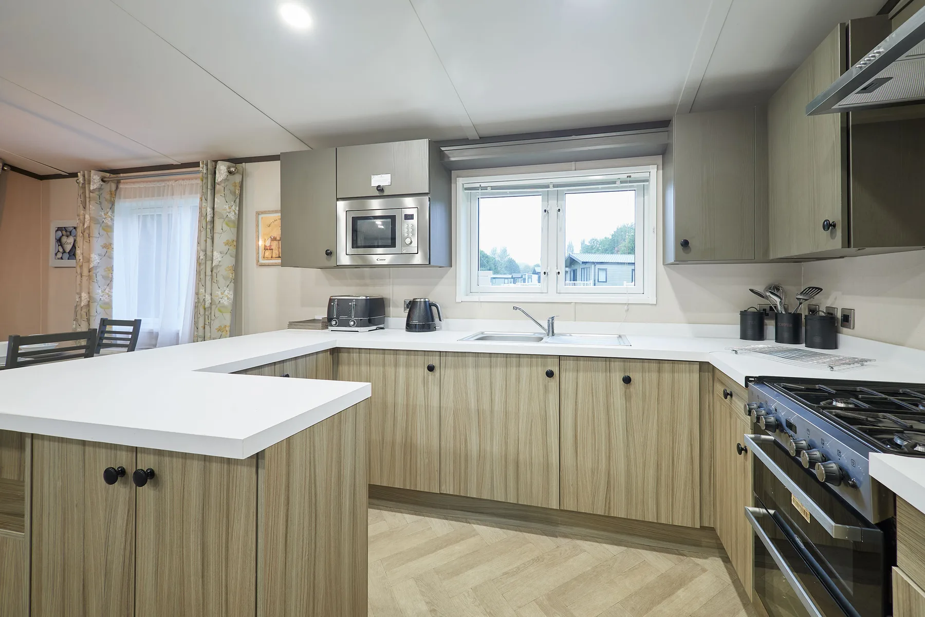 A bright kitchen with light wood cabinets, white counters, and a window over the sink.