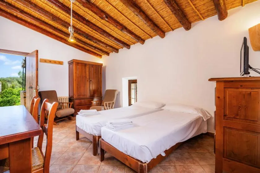 A bedroom with two beds, wooden furniture, and an exposed timber ceiling.