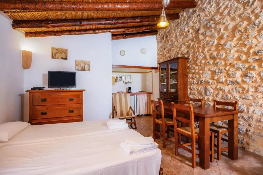 A bedroom with a bed beside a wooden dining table and chairs.