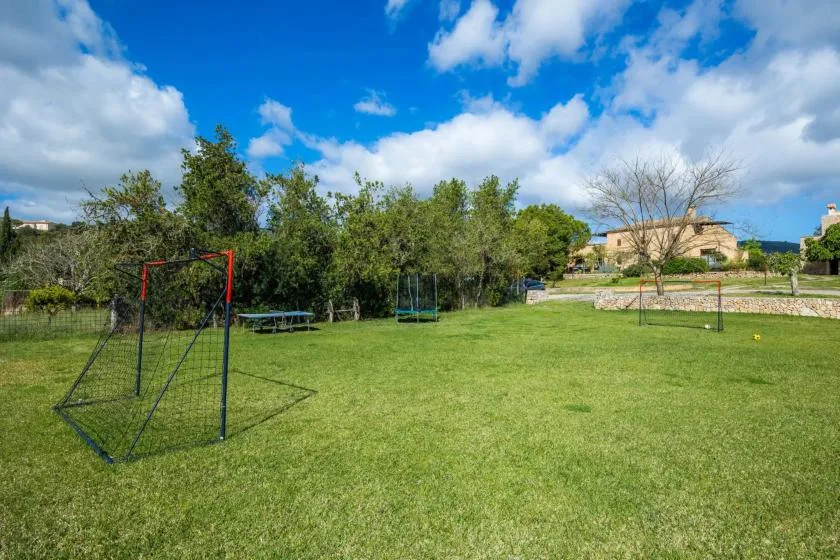 A grassy outdoor play area with several soccer goals beneath a partly cloudy sky.