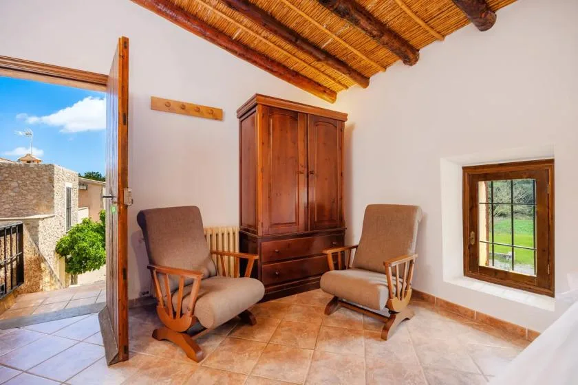 A sitting area with two upholstered seats and a wooden cabinet beneath a timber ceiling.