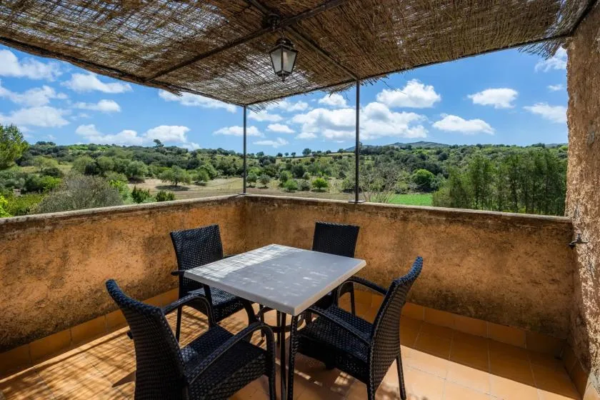 A shaded outdoor dining area overlooks green hills and open countryside.