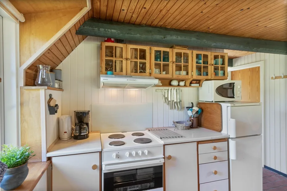 A compact kitchen with a stove, countertop, and wooden cabinets.