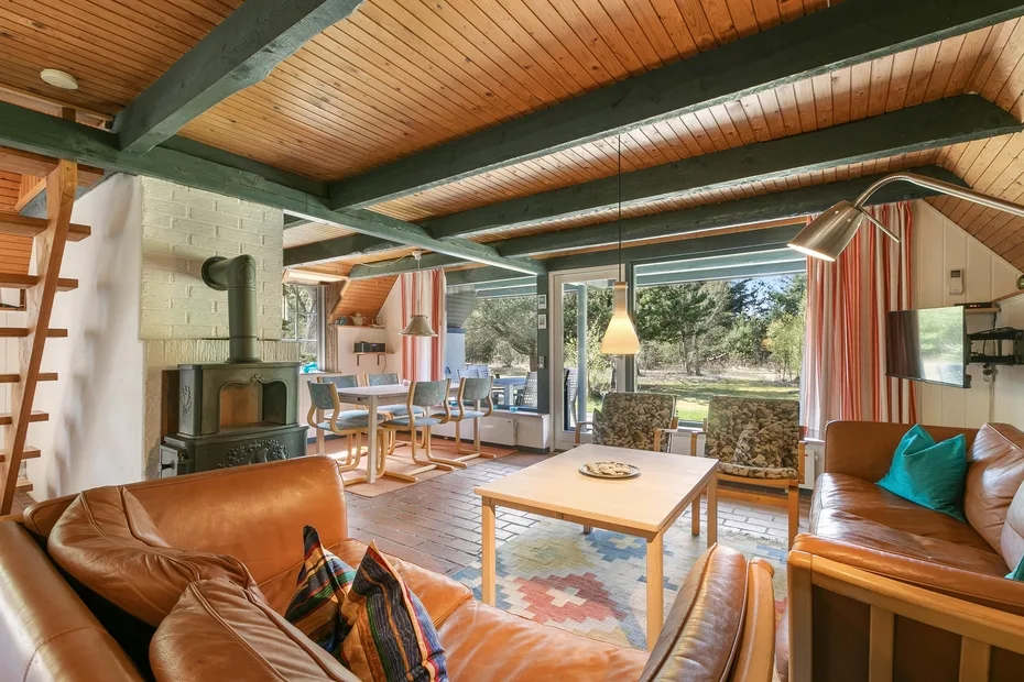 A living room with seating, a coffee table, and large windows overlooking greenery.
