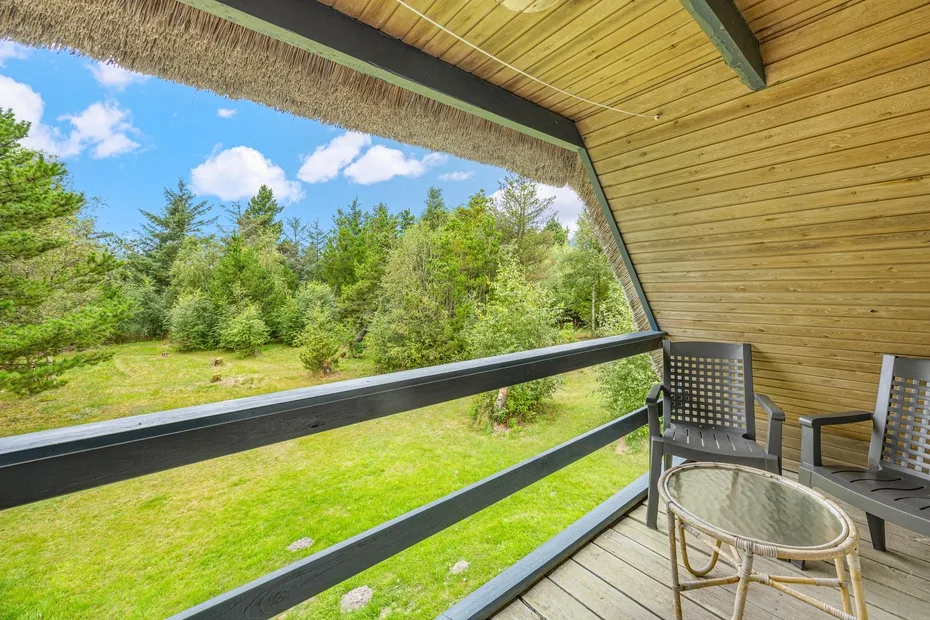A covered outdoor deck overlooks a grassy clearing and trees.