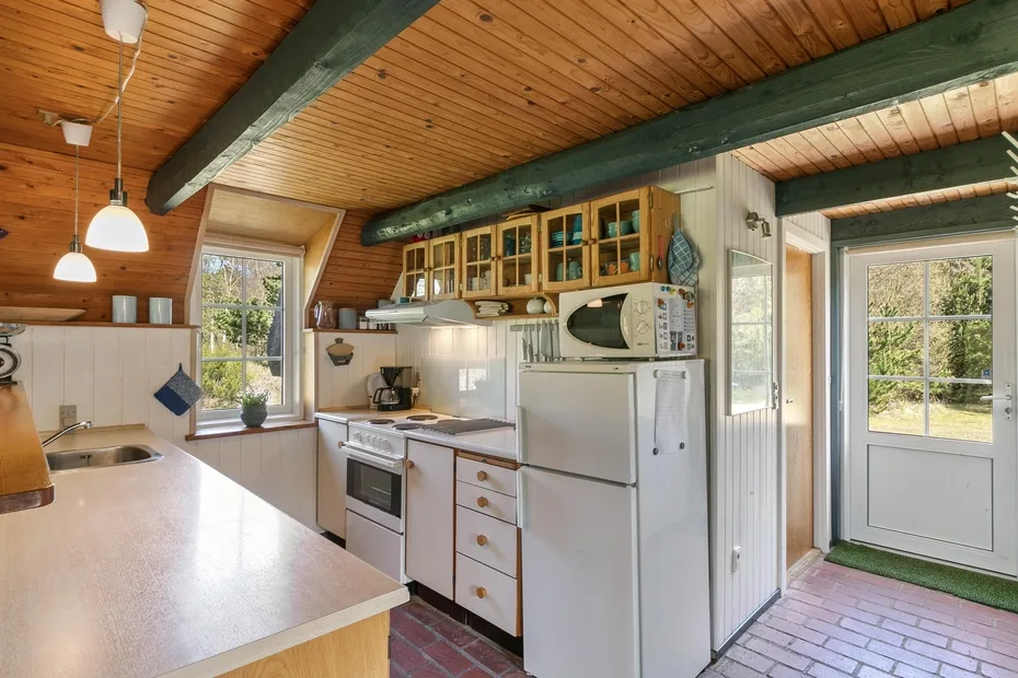 A bright kitchen with wooden cabinets and a refrigerator beside a glass door.