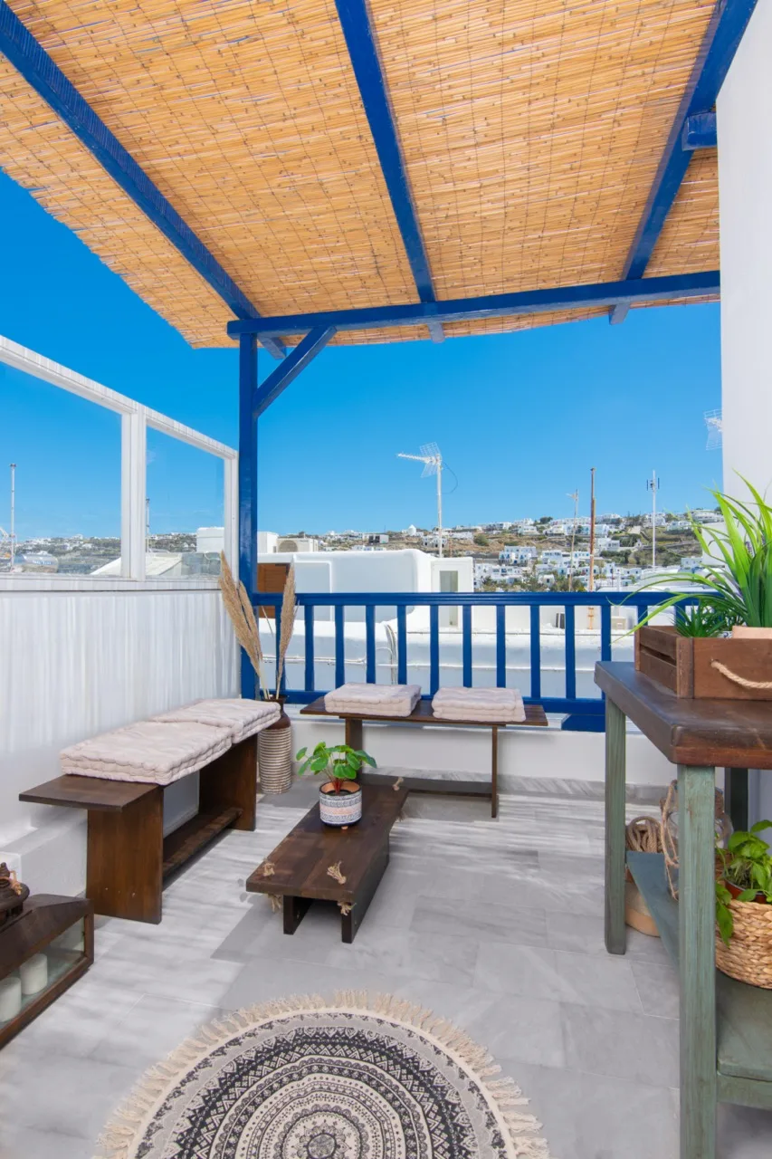 A covered balcony with seating and a view of the surrounding buildings.