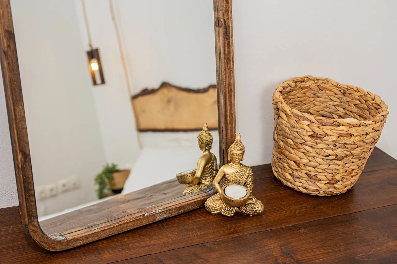 A wooden dresser holds a woven basket and small decorative figurines beside a mirror.