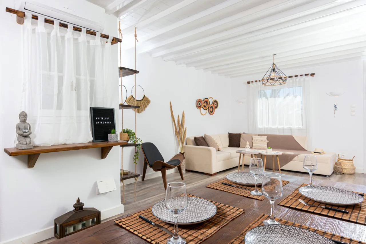 Una sala luminosa con asientos, una mesa baja y vigas blancas en el techo.