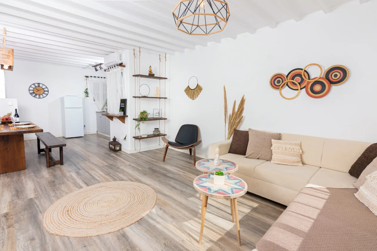 Una sala luminosa con asientos, una mesa de centro y una cocina abierta.