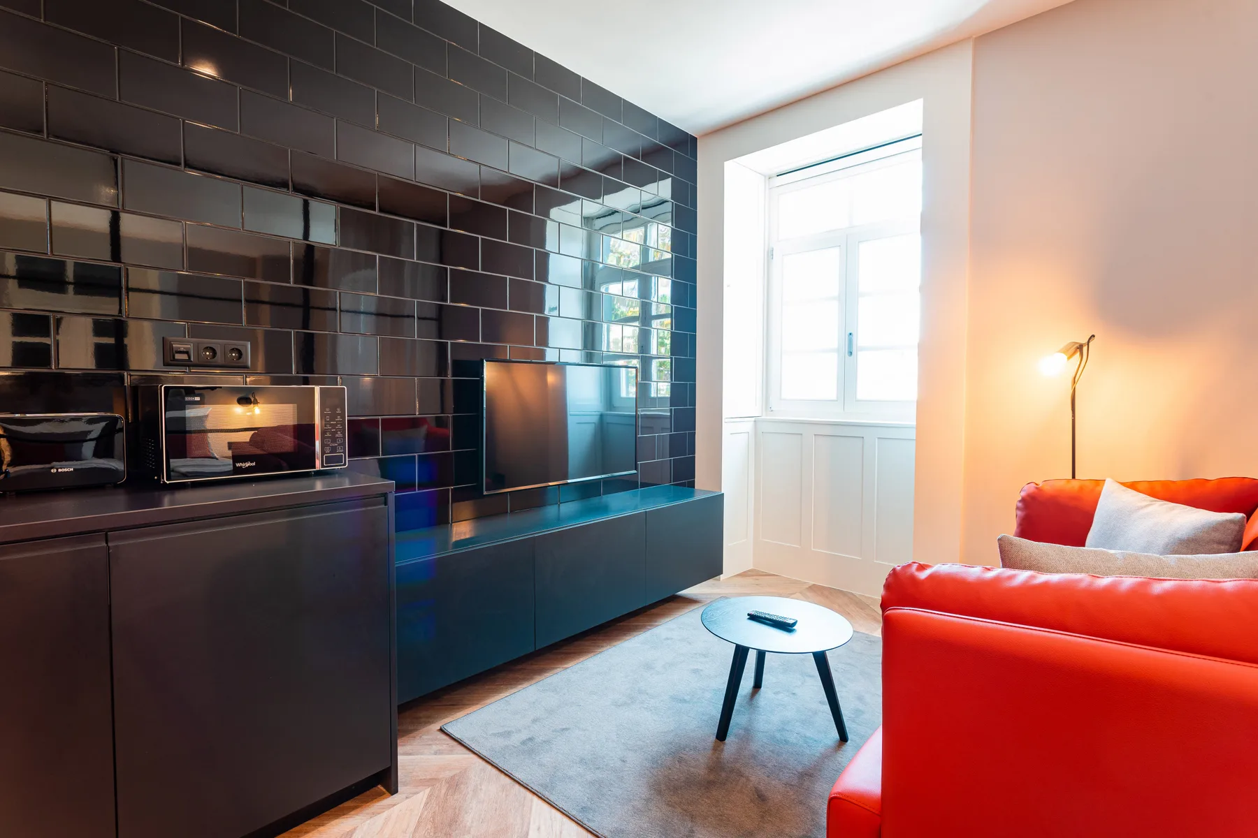 A modern living area with a red sofa, coffee table, and open kitchen.