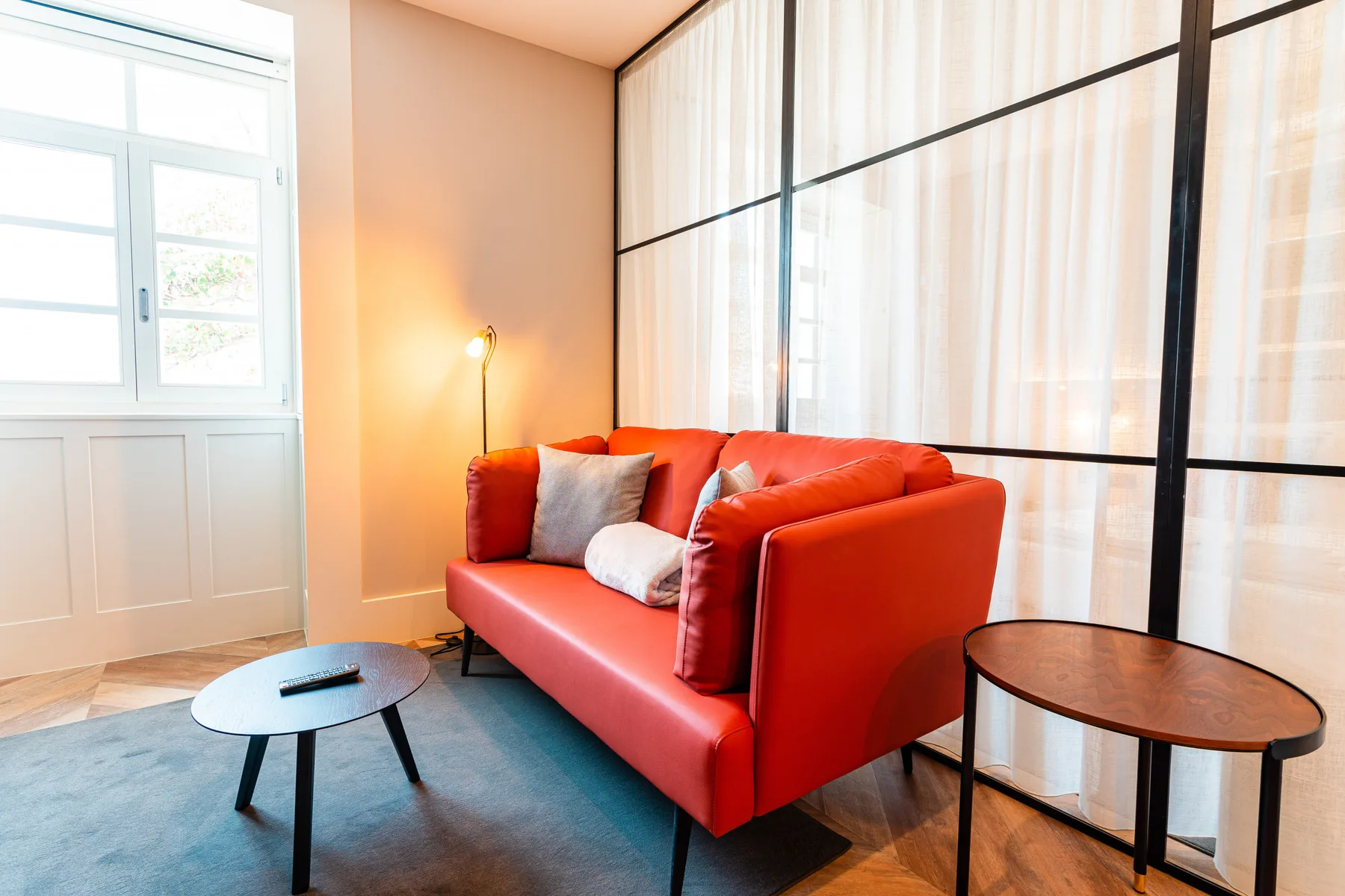 Living room with red seating beside a large curtained window.