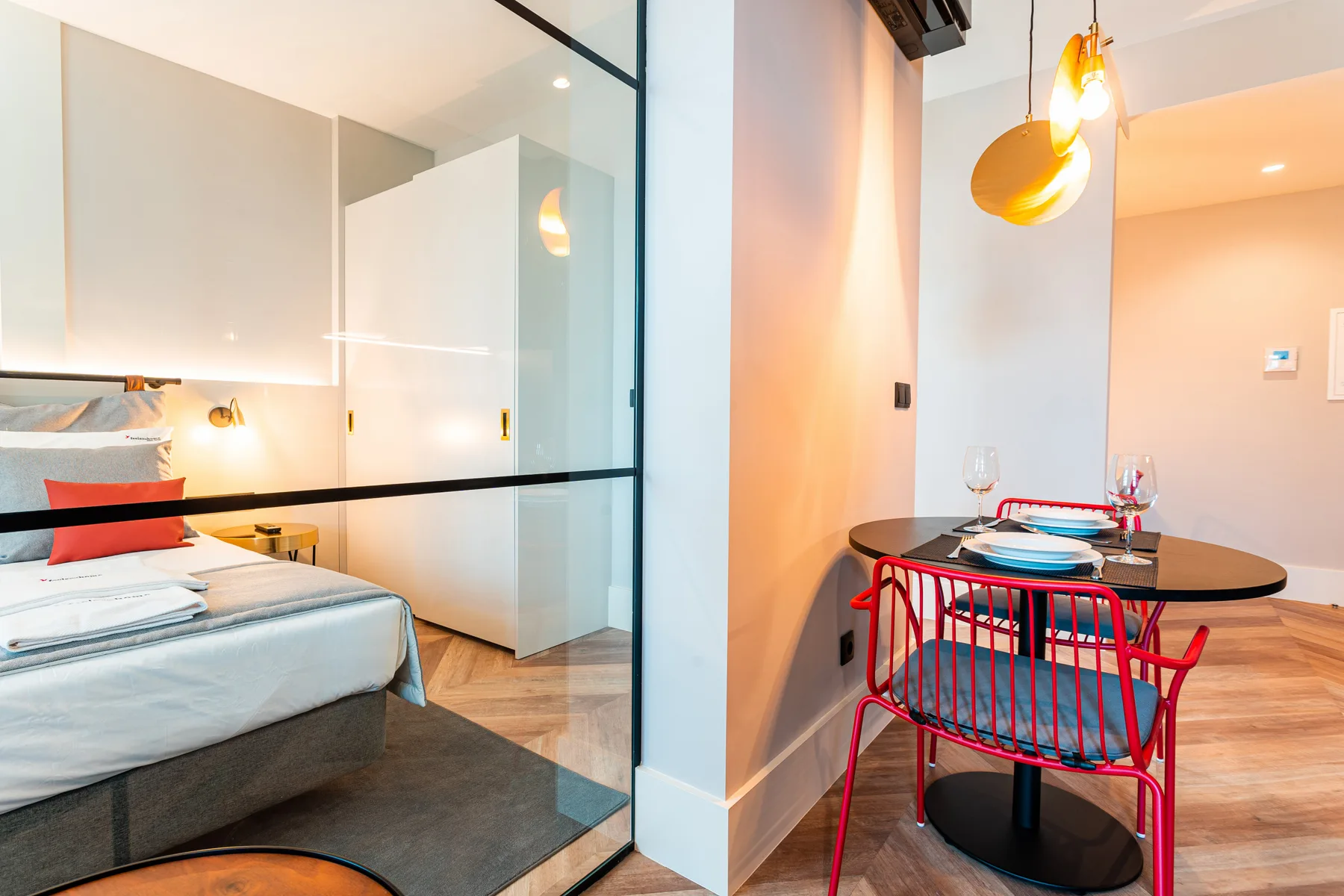 Un dormitorio y una zona de comedor están separados por un panel de vidrio.