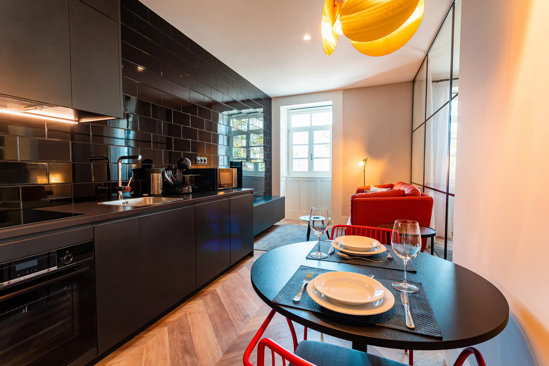 Una cocina moderna y zona de comedor con una mesa ovalada oscura preparada con platos.