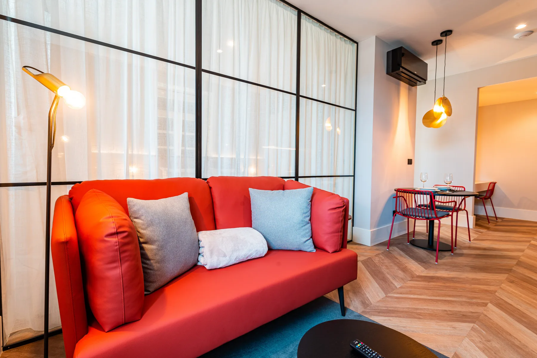 Una sala de estar con asientos rojos junto a una pequeña mesa de comedor.