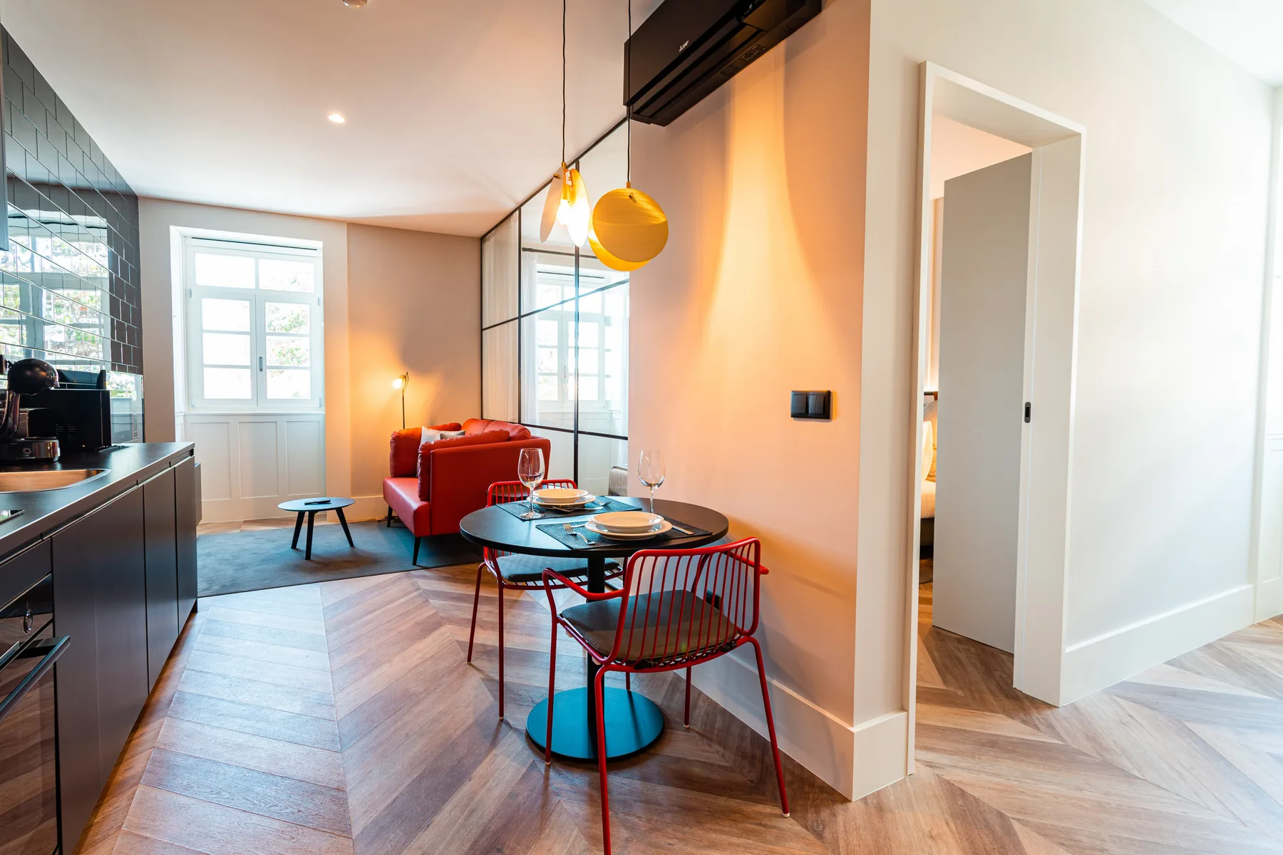 Una zona abierta de comedor y estar tiene una mesa, asientos rojos y una encimera de cocina.