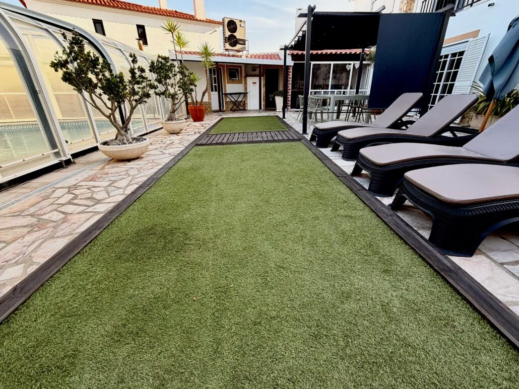 Garden with lawn, sun loungers and covered pool