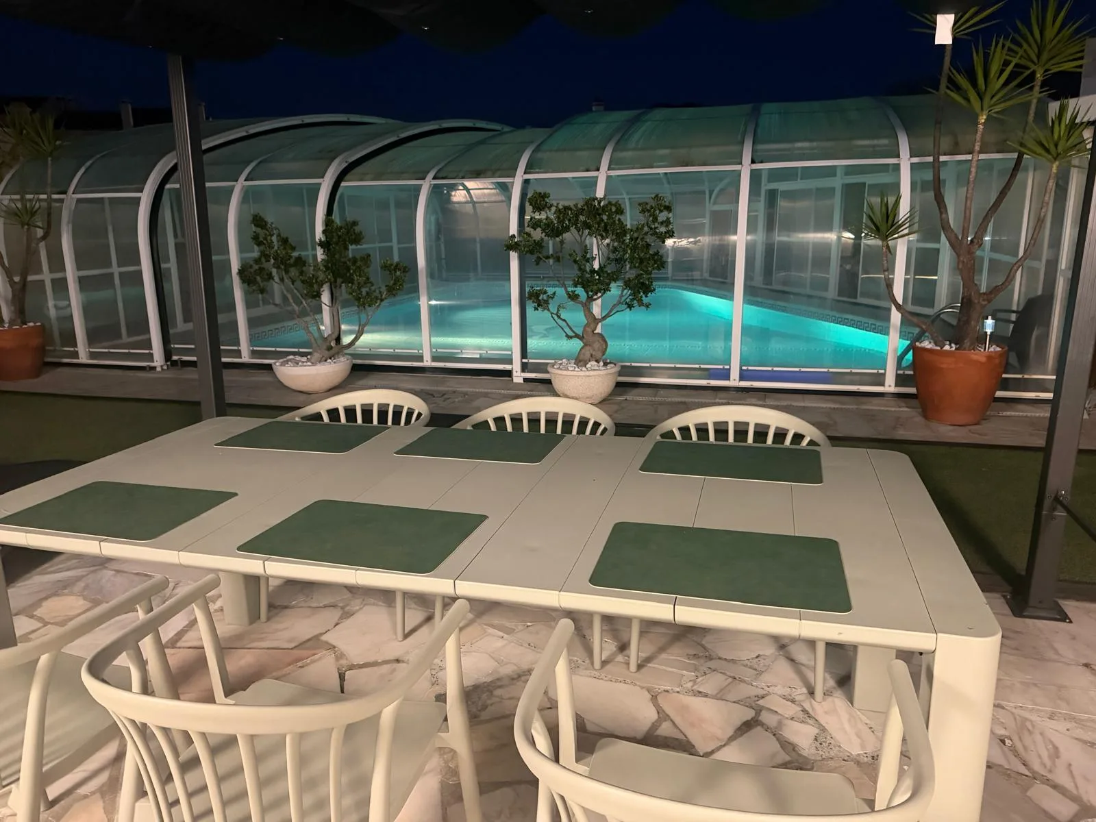 Piscina cubierta climatizada iluminada por la noche con tumbonas