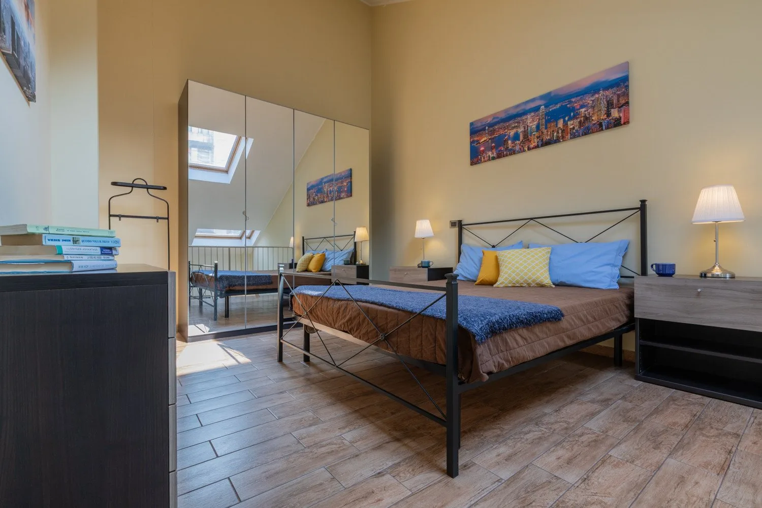 A bedroom with a bed, mirrored wardrobe, and bedside tables.