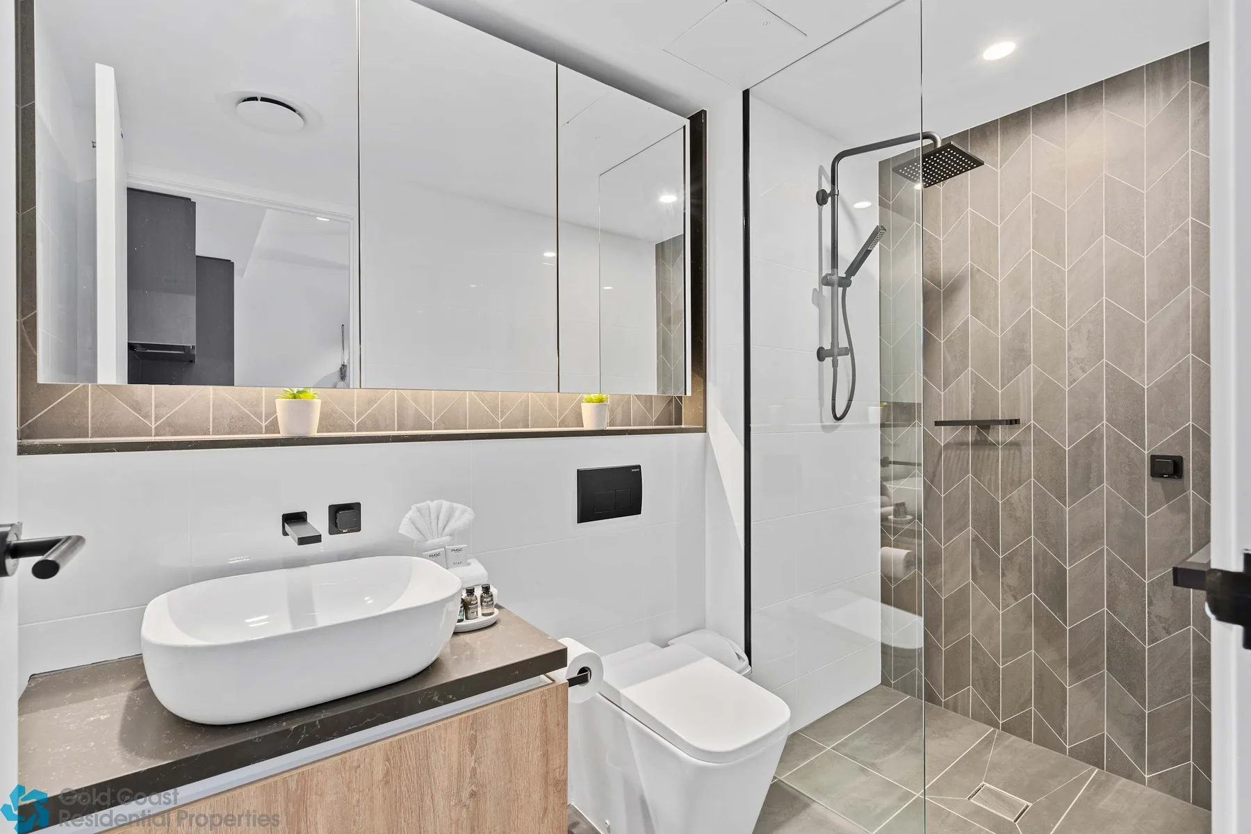 Un baño moderno cuenta con un lavabo sobre encimera junto a una ducha de vidrio.