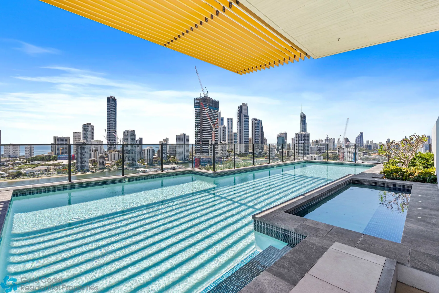 Una piscina en la azotea ofrece vistas al perfil urbano bajo un toldo a rayas.