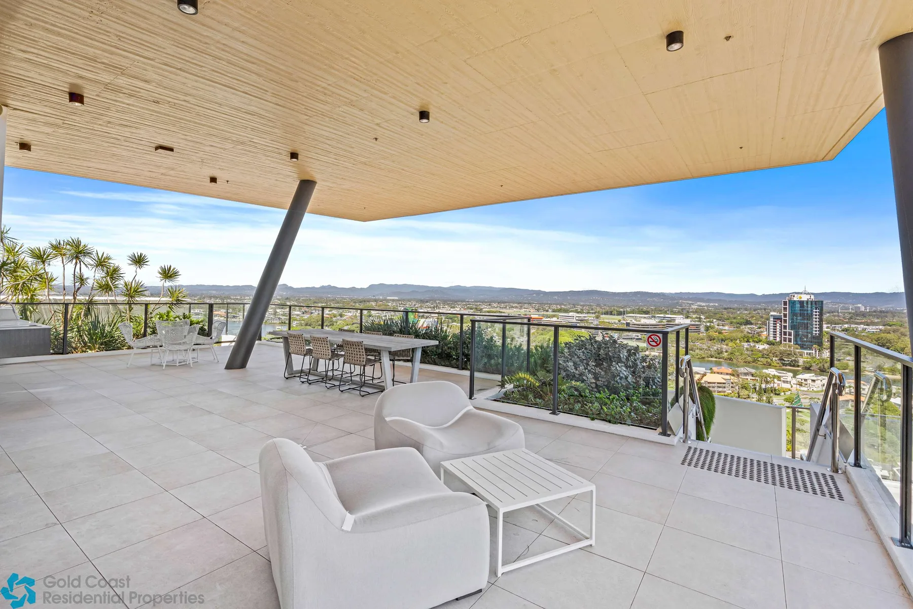 Una amplia terraza exterior tiene asientos y ofrece vistas a un paisaje urbano y costero.