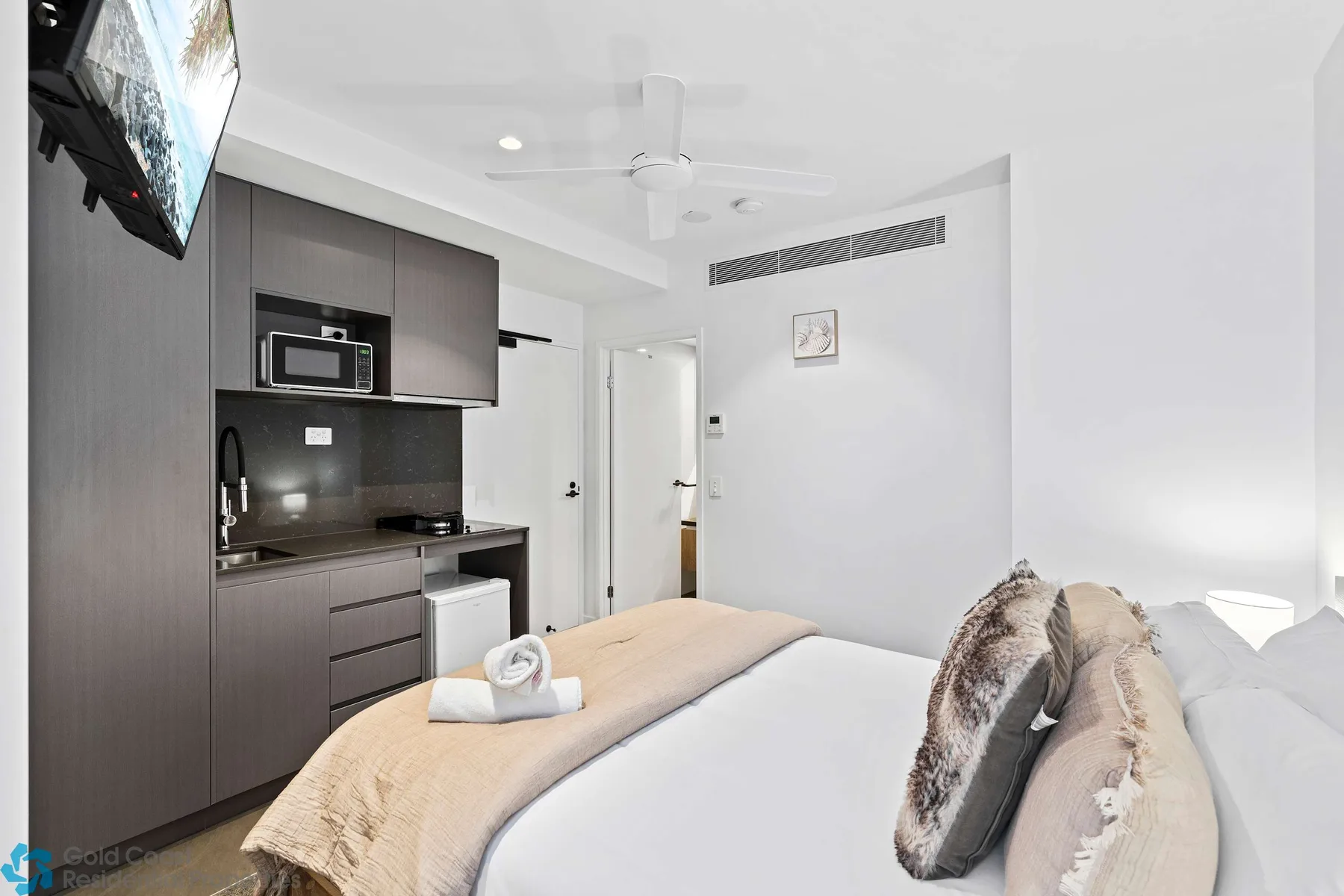 Un dormitorio luminoso con una cama y una pequeña cocina junto a la pared.
