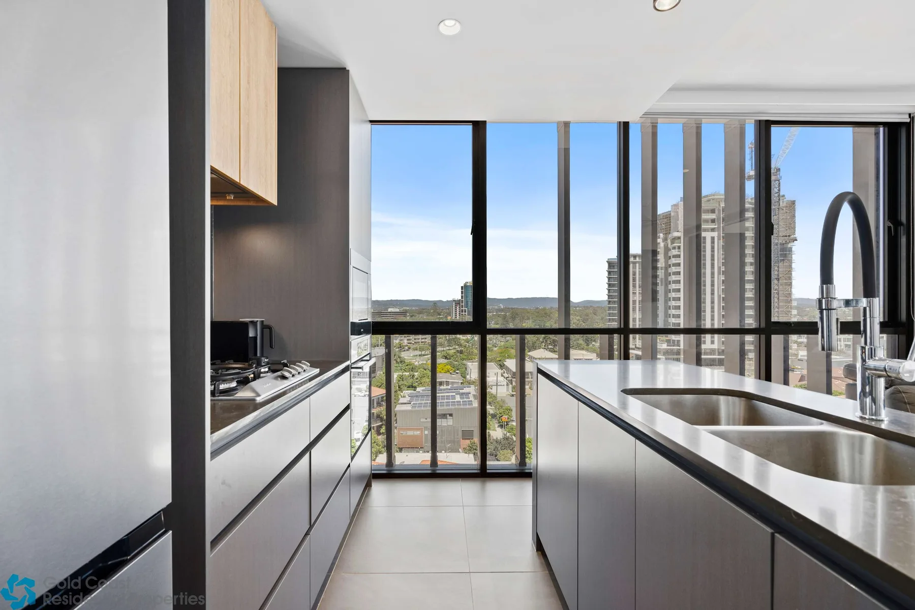Una cocina moderna con una isla central y grandes ventanales con vistas a edificios de la ciudad.