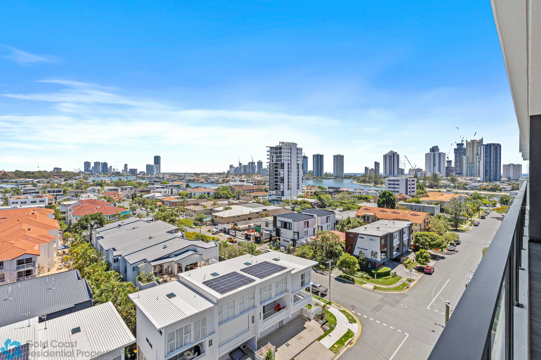 Panorámica urbana desde las alturas, con edificios residenciales y torres bajo un cielo azul.