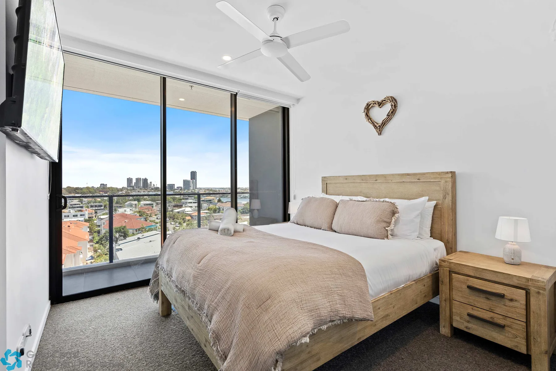 Un dormitorio con una cama junto a grandes ventanas con vistas a la ciudad.